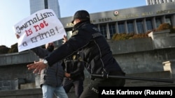 Polis jurnalistlərin Bakıda parlament binası qarşısında yeni media qanun layihəsinə qarşı aksiyası zamanı etirazçının qarşısını alır. 2021