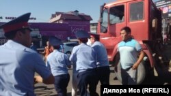 Полиция қызметкерлері орталық базарда дүңгіршектерін сүруге қарсылық танытқан адамды ұстап әкетіп барады. Шымкент, 30 шілде 2018 жыл.